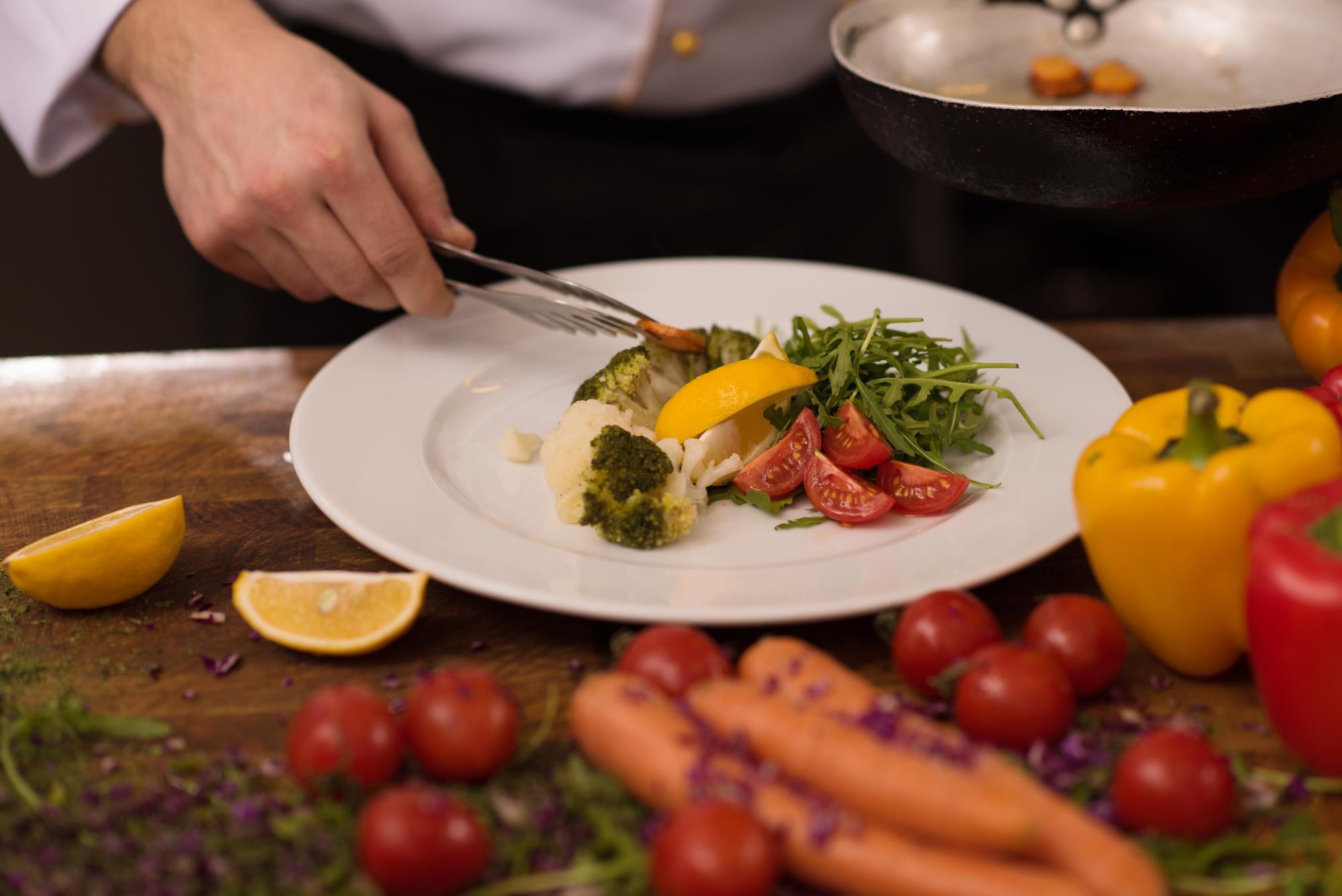 Chef demonstrating plating technique on wooden table